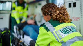 Paramedic in reflective jacket watching over ambulance care.
